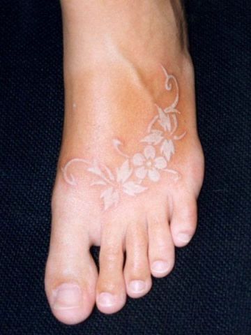 white ink tattoo flowers on a foot