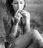 tattooed girl with dreadlocks eating on grass