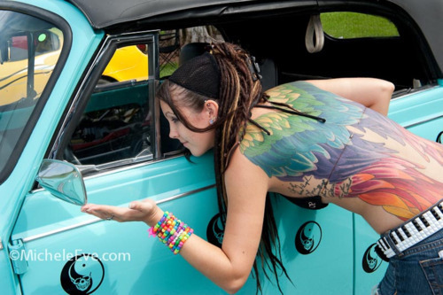 tattooed girl with dreadlocks rainbow wings blue car