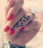 tiny stars tattoo on red polished hand