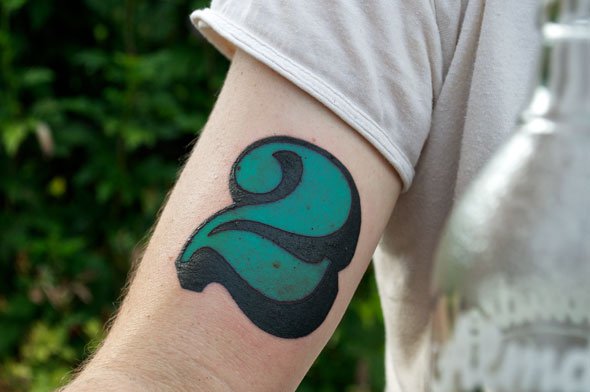 typographic tattoo green  number on arm