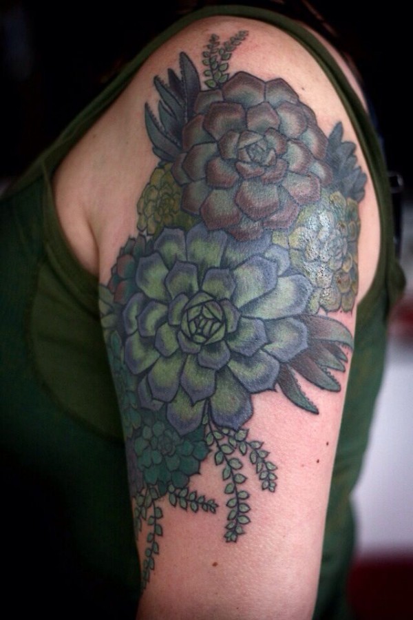 alice carrier tattoo blue and green coloured flowers on upper arm