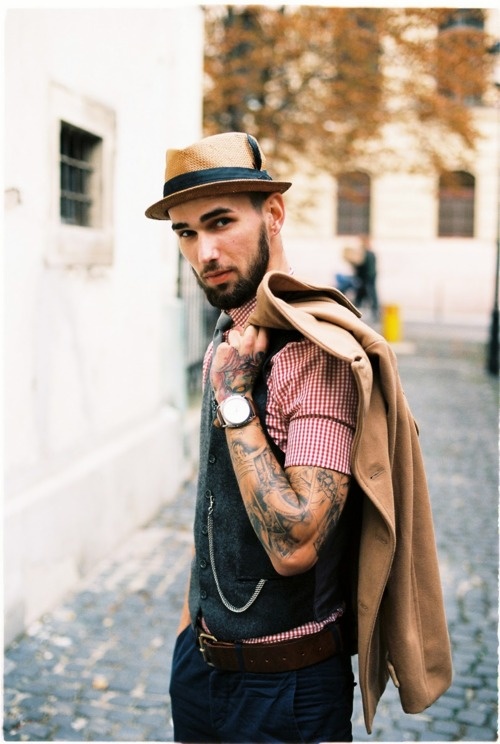 man with tattoos holding a jacket