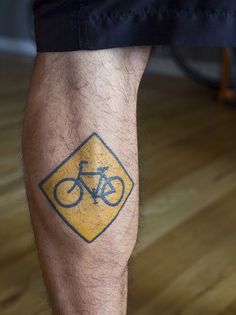 Bicycle sign tattoo on leg