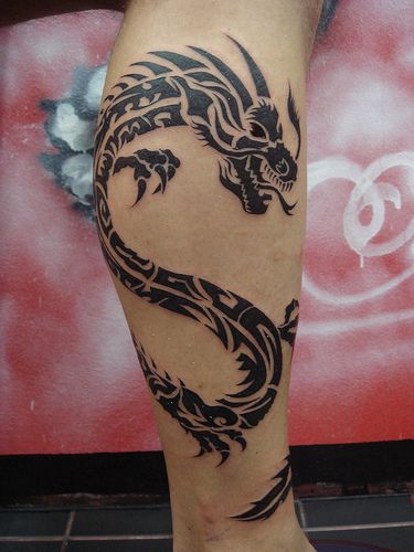 Black angry dragon tribal tattoo on leg