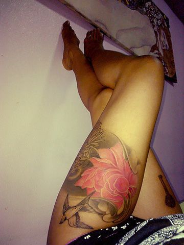 Black bird and pink flower tattoo on leg