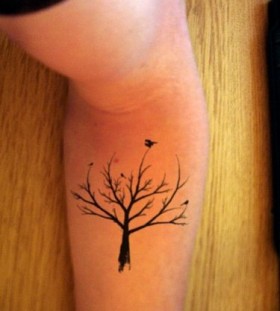 Black bird and tree tattoo on arm