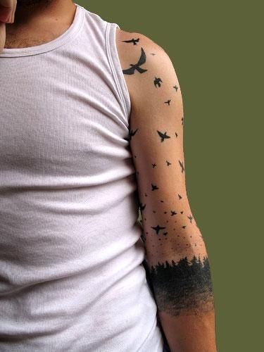 Black forest and bird tattoo on arm