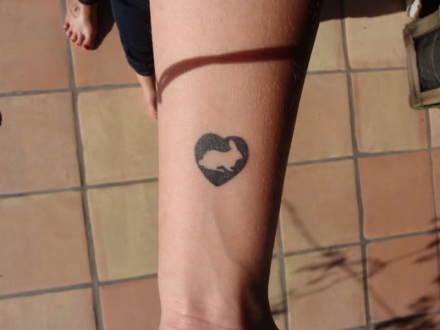 Black heart and rabbit tattoo on arm