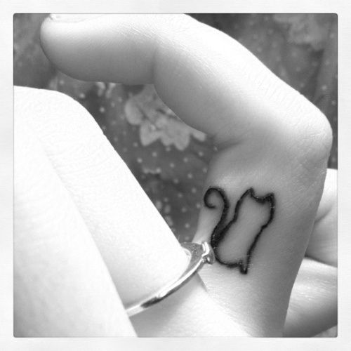 Black ornament of cat tattoo on finger