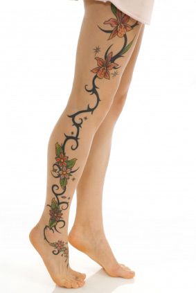 Black ornaments of flowers and tribal tattoo on leg