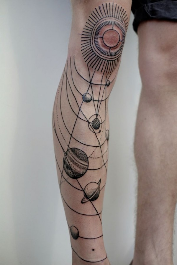 Black ornaments of sun tattoo on leg