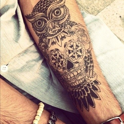 Black owl and skull tattoo on arm