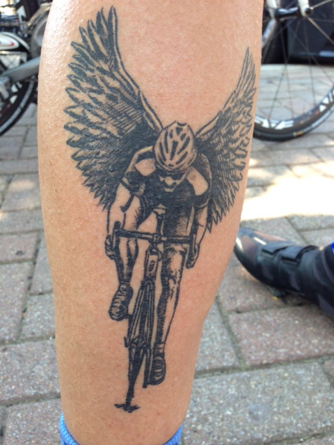 Black wings and bicycle tattoo on leg