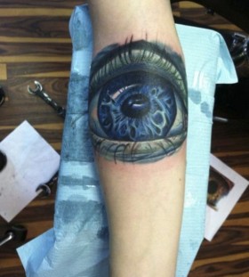 Blue and black eye tattoo on arm