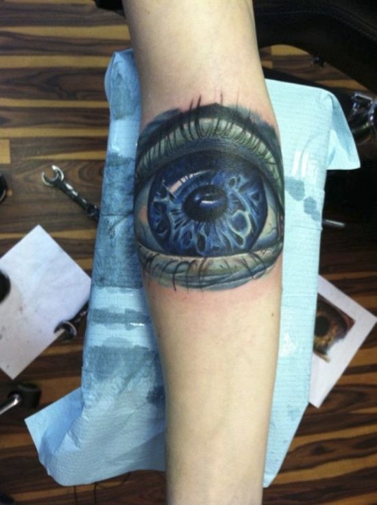 Blue and black eye tattoo on arm