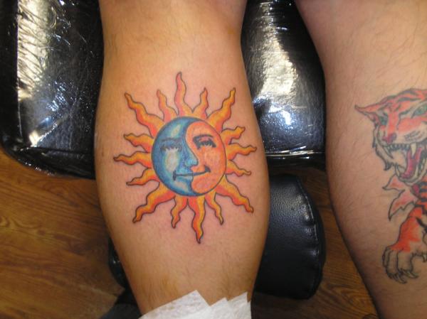 Blue and yellow sun tattoo on leg