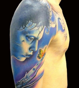 Blue face and butterfly tattoo on arm