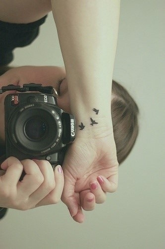 Canon camera and black bird tattoo on arm