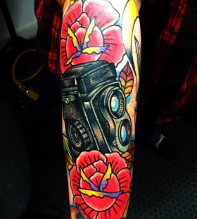 Colorful flowers and camera tattoo on arm