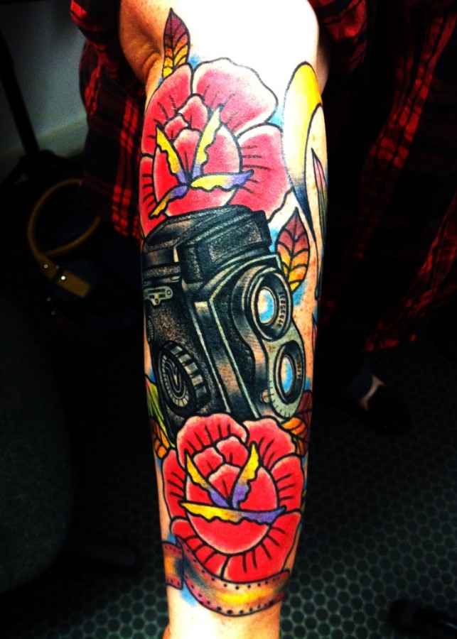 Colorful flowers and camera tattoo on arm