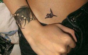 Feather and crane origami tattoo on arm