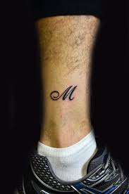 M letter tattoo on leg