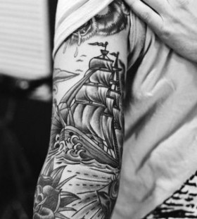 Men's black ship tattoo on arm
