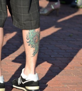 Men's green eye tattoo on leg