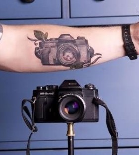 Realistic black camera tattoo on arm