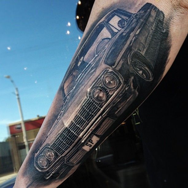 Realistic black car tattoo on arm