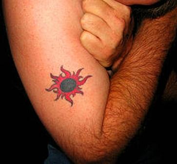 Red and black sun tattoo on arm