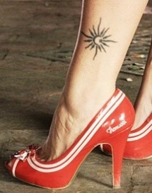 Red high-heels and sun tattoo on leg