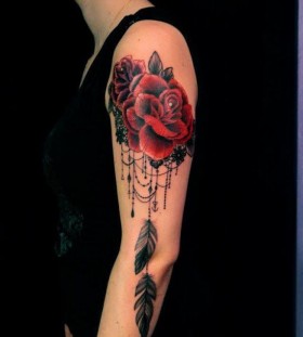 Red rose, feather and lace tattoo on arm