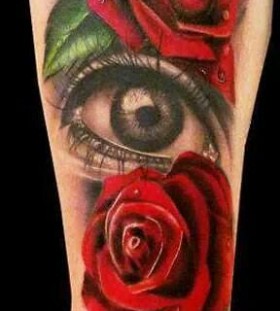 Red roses and amazing eye tattoo on arm