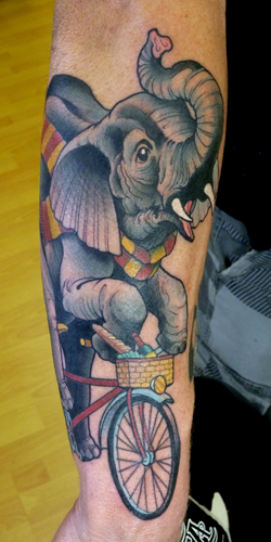 Riding elephant with bicycle tattoo on arm