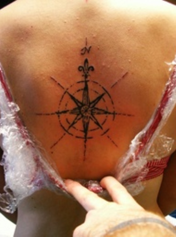 Simple women’s compass tattoo on back