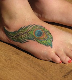Women's leg red nails and peacock tattoo on leg