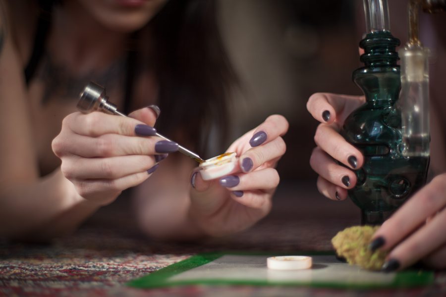 Women with nicely manicured fingernails use a titanium dabber to