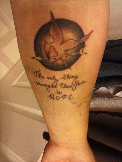 Cool mockingjay logo arm tattoo