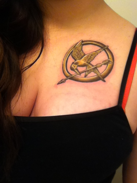 Golden mockingjay logo chest tattoo