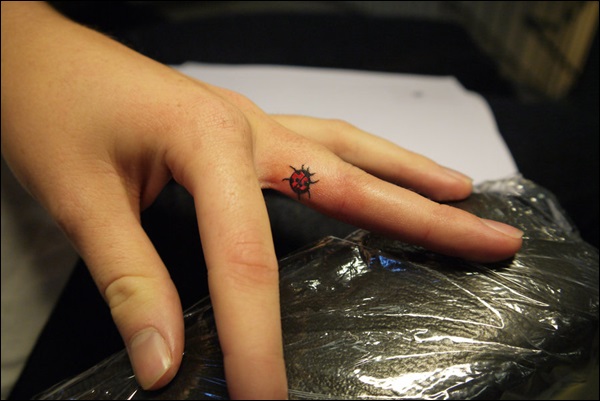 Small ladybug finger tattoo